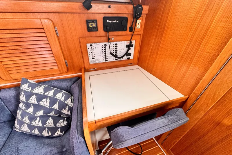Navigation station in 2001 Catalina 36 MkII sailboat with control panel and nautical-themed cushion.