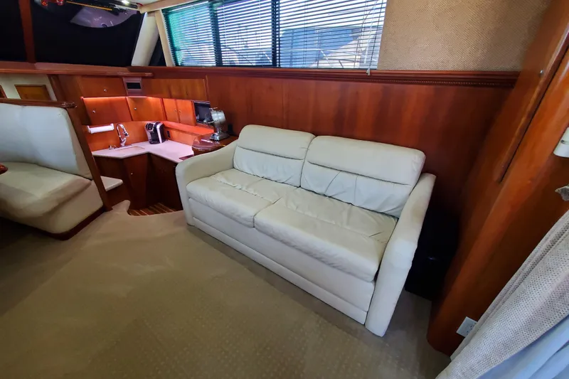 Interior of 2000 Silverton 42 Convertible yacht with white sofa and wooden cabinetry.