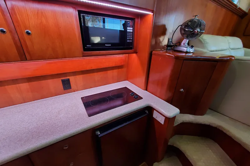 Interior of 2000 Silverton 42 Convertible yacht kitchen with stove, microwave, and fan.