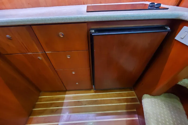 Interior of 2000 Silverton 42 Convertible yacht with wooden cabinetry and compact fridge.