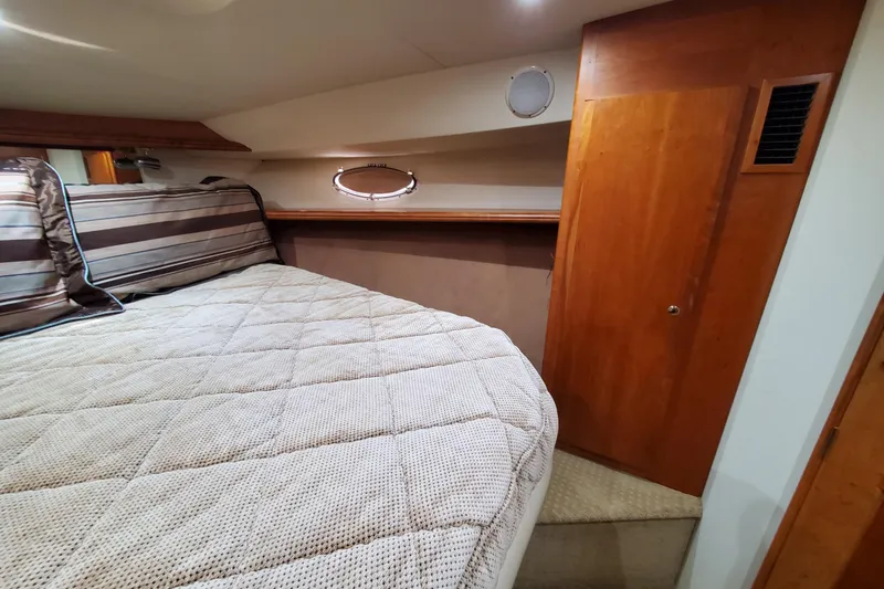 Interior cabin of a 2000 Silverton 42 Convertible yacht with cozy bedding and wooden accents.