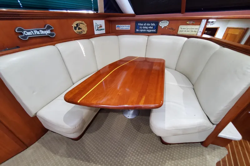 Luxurious dining area in a 2000 Silverton 42 Convertible yacht with plush seating and wooden table.