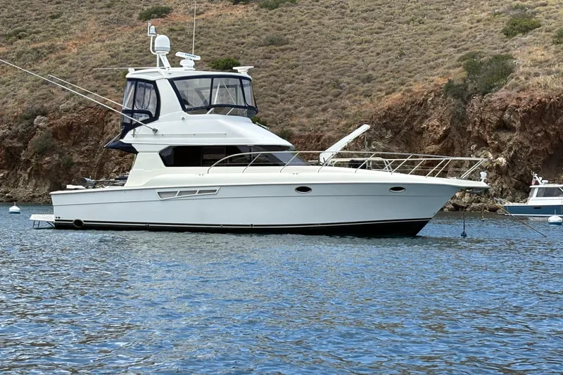 2000 Silverton 42 Convertible yacht anchored in scenic coastal waters.