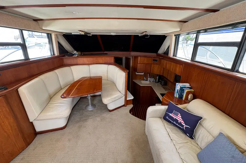 Interior of 2000 Silverton 42 Convertible yacht with cozy seating and elegant wood finishes.