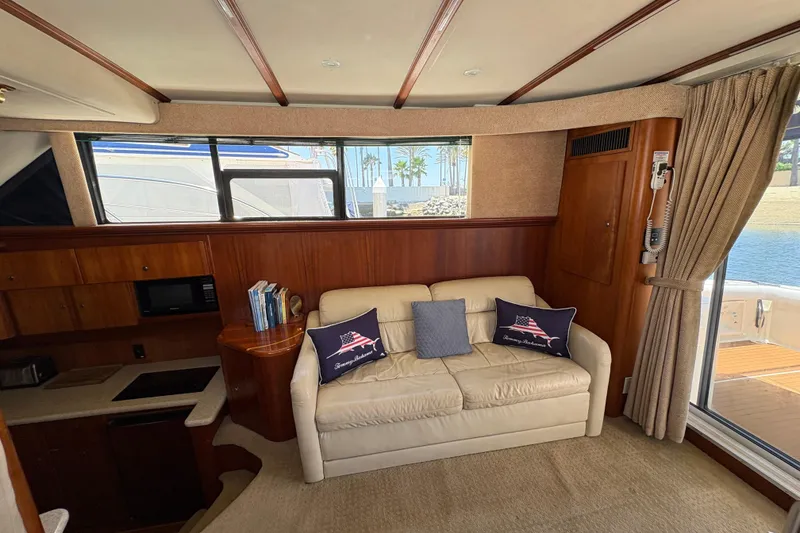 Interior of 2000 Silverton 42 Convertible yacht with sofa, pillows, and kitchenette.