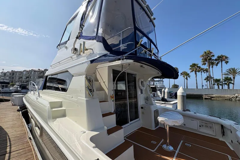 2000 Silverton 42 Convertible yacht docked at marina with palm trees in background.