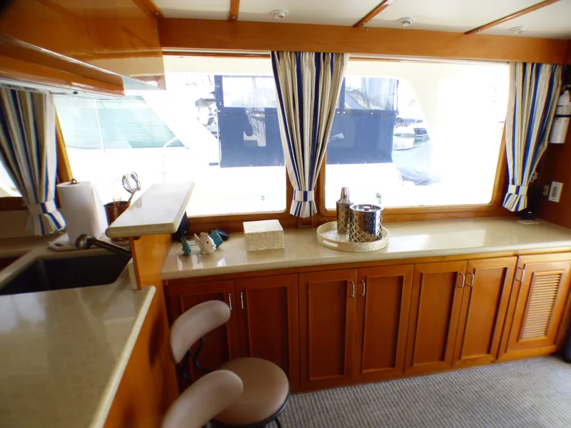 Interior of 1987 MedYacht Mallorca 50 with wooden cabinets and striped curtains.