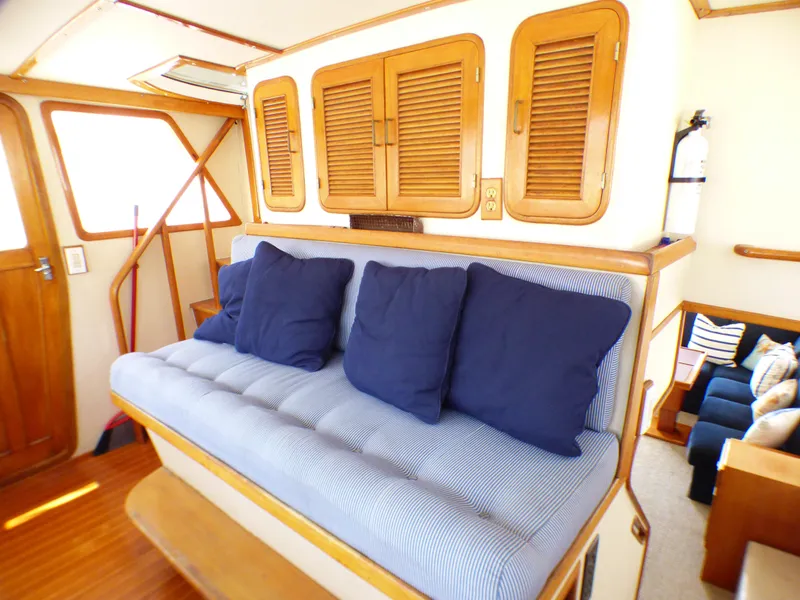 Cozy interior of 1987 MedYacht Mallorca 50 with blue cushions and wooden accents.