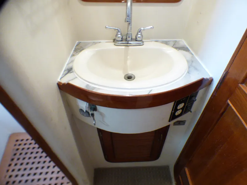 Compact bathroom sink on 1987 MedYacht Mallorca 50, featuring marble countertop and chrome faucet.