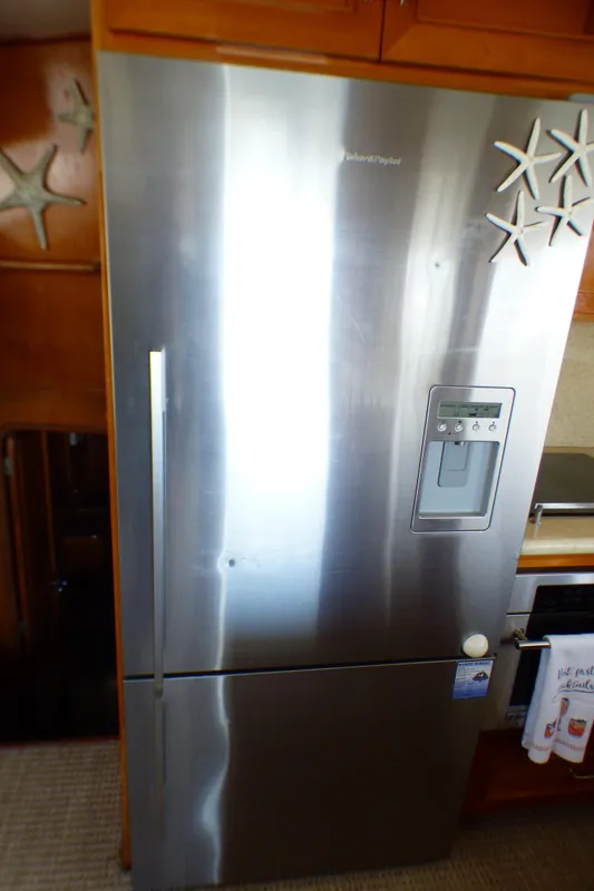 Stainless steel refrigerator inside 1987 MedYacht Mallorca 50, adorned with starfish magnets.