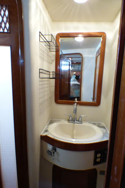 Compact bathroom sink area on 1987 MedYacht Mallorca 50 with mirror and shelving.