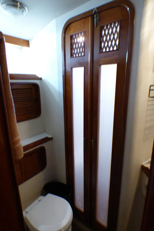 1987 MedYacht Mallorca 50 yacht bathroom with wooden doors and compact toilet.