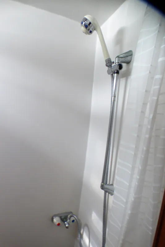 Shower area in 1987 MedYacht Mallorca 50, featuring adjustable showerhead and white tiled wall.
