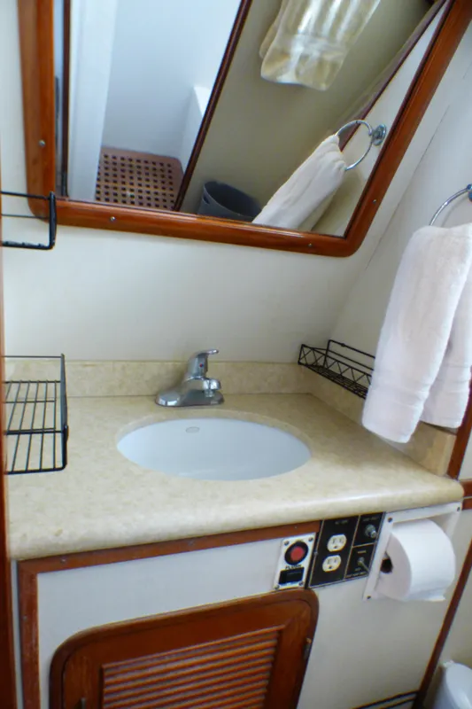 Bathroom sink area on a 1987 MedYacht Mallorca 50, featuring a mirror and towel rack.