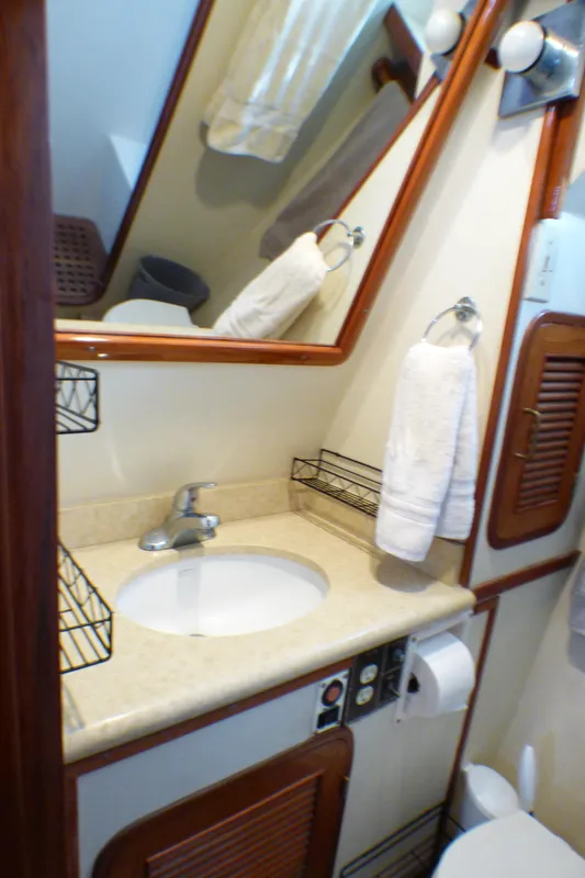 Bathroom interior of 1987 MedYacht Mallorca 50, featuring sink, mirror, and wooden accents.