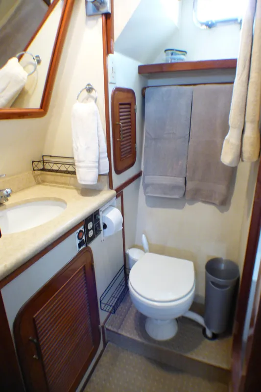 Compact bathroom in 1987 MedYacht Mallorca 50, featuring sink, toilet, and wooden cabinetry.