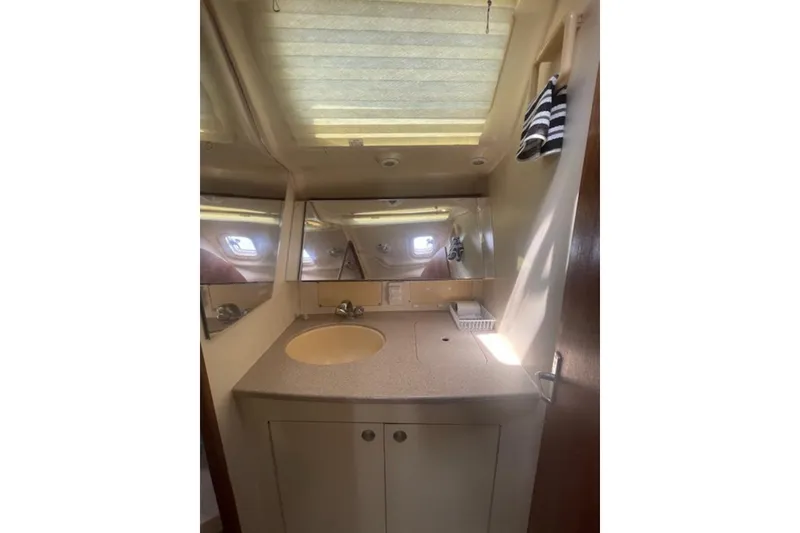 Bathroom interior of 2001 Hunter 380 yacht with sink, mirror, and striped towels.