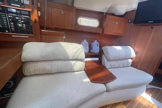 Interior of 2001 Hunter 380 yacht with cushioned seating and wooden cabinetry.