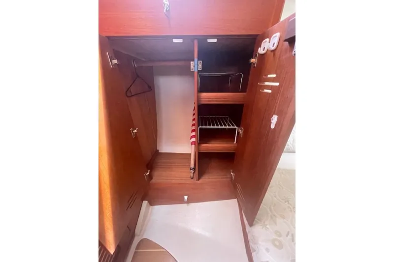 Wooden interior storage cabinet in a 2001 Hunter 380 sailboat, featuring shelves and hangers.