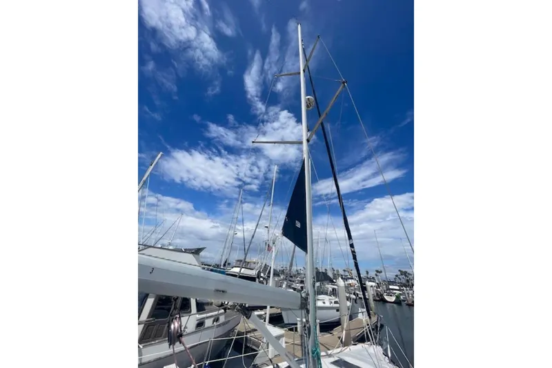Sailboat mast of 2001 Hunter 380 against a vibrant blue sky at marina.