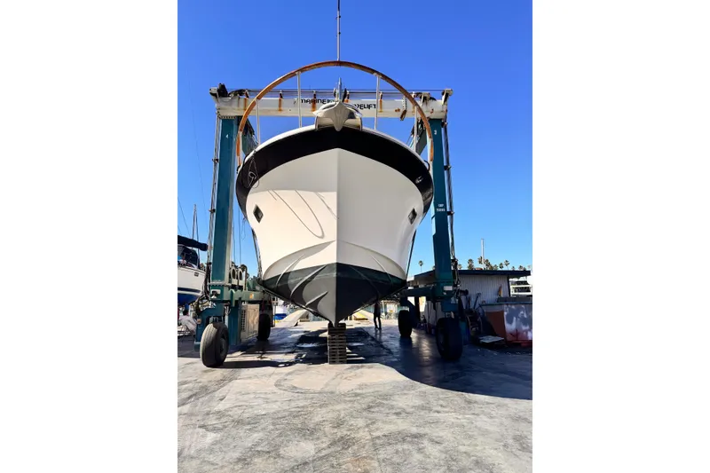 1988 Overseas PT52 Cockpit Motoryacht in dry dock, front view under clear blue sky.