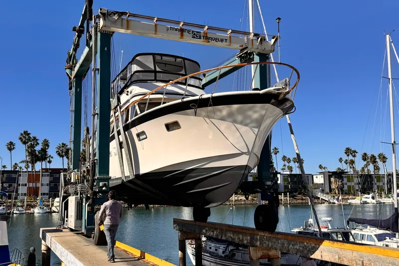 1988 Overseas PT52 Cockpit Motoryacht lifted at marina, clear blue sky, palm trees in background.