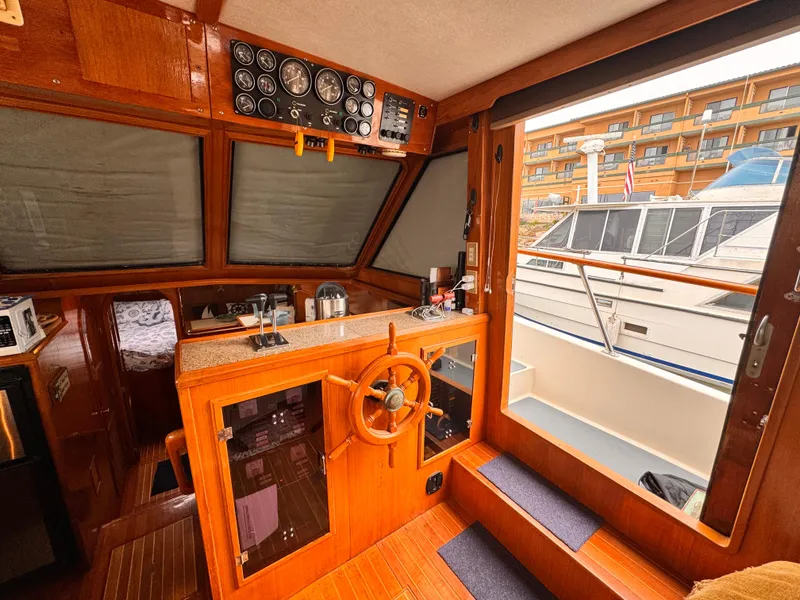 1988 Overseas PT52 Cockpit Motoryacht interior with wooden helm, gauges, and marina view.