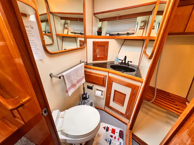 1988 Overseas PT52 Cockpit Motoryacht bathroom with wooden cabinetry, sink, and toilet.