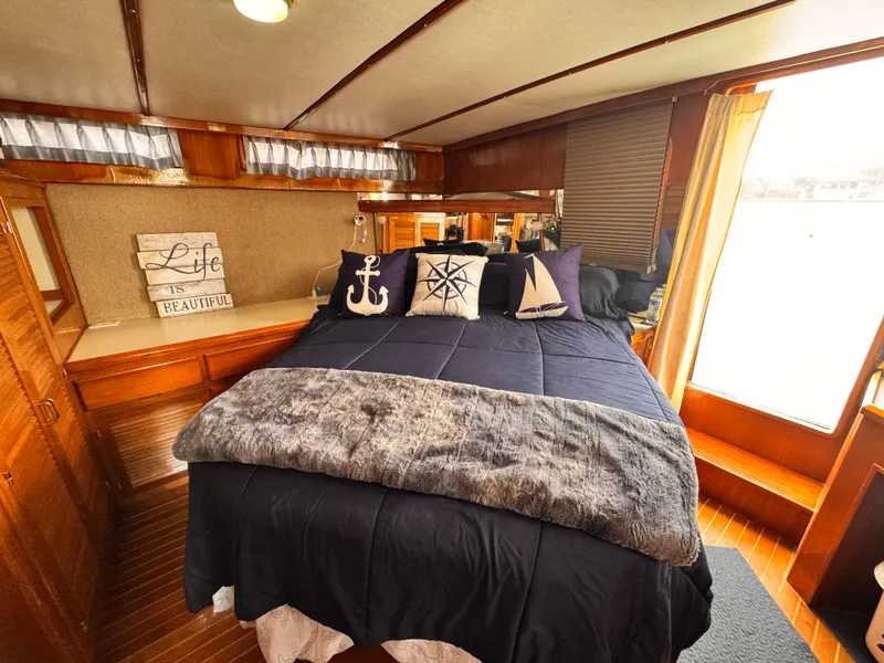 Luxurious bedroom in 1988 Overseas PT52 Cockpit Motoryacht with nautical-themed decor.