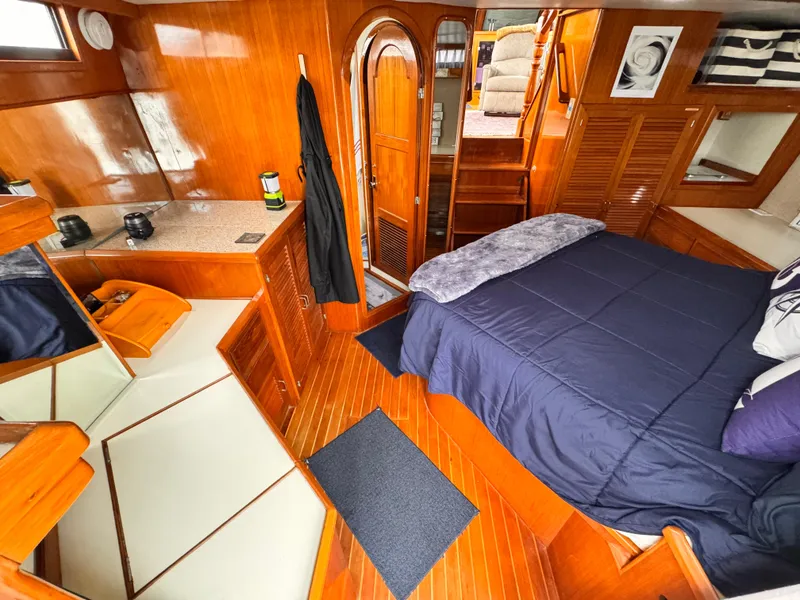 Luxurious 1988 Overseas PT52 Cockpit Motoryacht interior with wood finish and cozy bedroom.