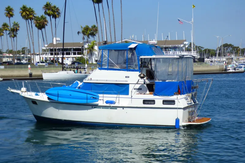 1985 Carver 3607 Aft Cabin Motor Yacht with blue canopy, docked in a marina.