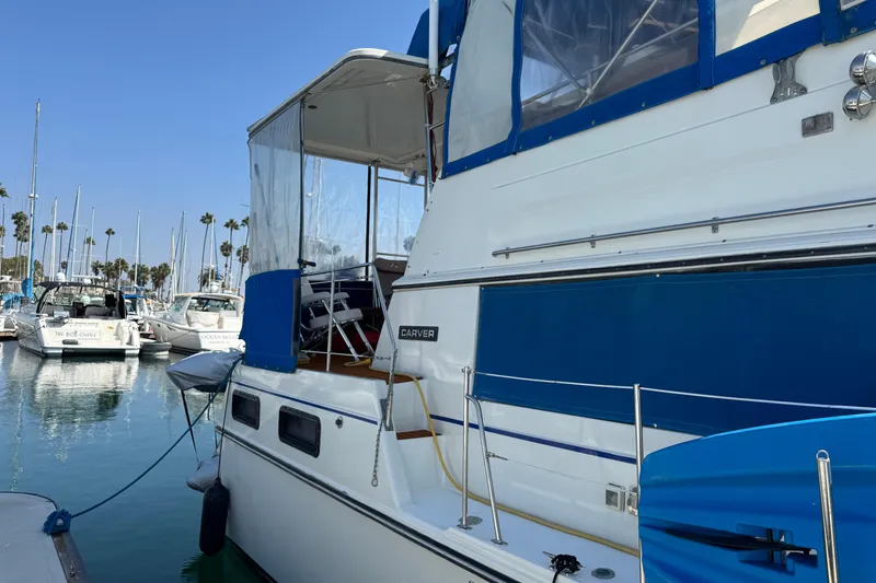 1985 Carver 3607 Aft Cabin Motor Yacht docked in a marina, clear blue sky.