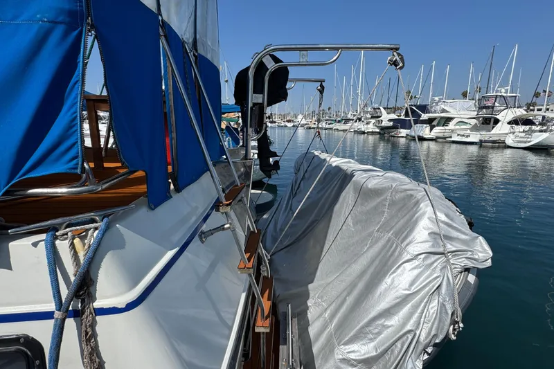 1985 Carver 3607 Aft Cabin Motor Yacht docked in marina, blue canopy, covered dinghy.