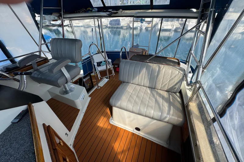 1985 Carver 3607 Aft Cabin Motor Yacht interior with seating and helm, docked at marina.