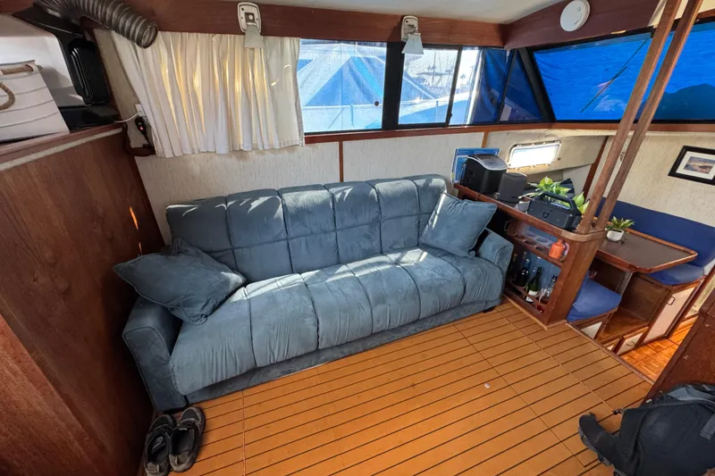 Interior of 1985 Carver 3607 Aft Cabin Motor Yacht with blue sofa and wooden flooring.