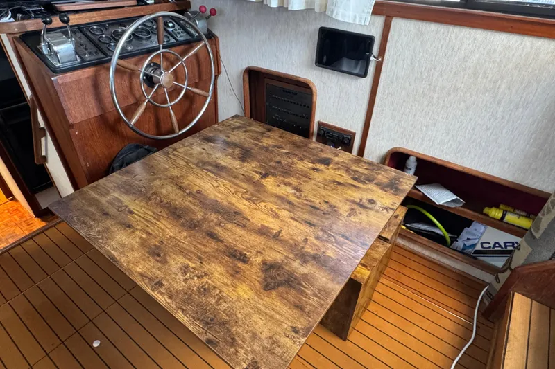 1985 Carver 3607 Aft Cabin Motor Yacht interior with wooden table and steering wheel.