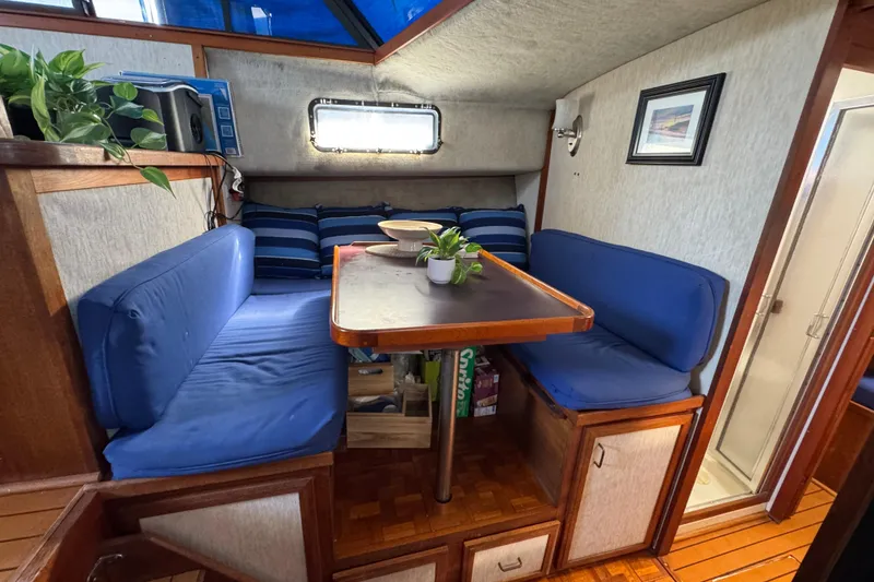 1985 Carver 3607 Aft Cabin Motor Yacht interior with cozy dining area and blue cushions.