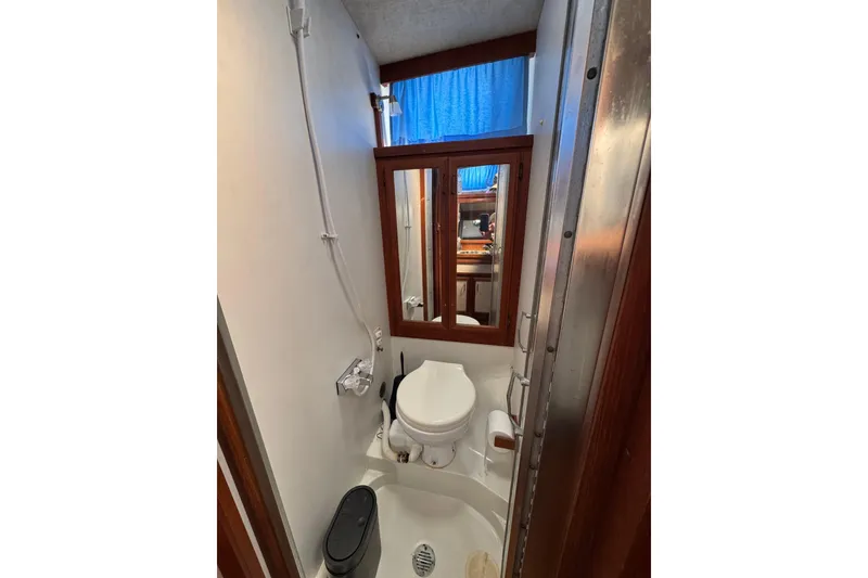 Bathroom interior of 1985 Carver 3607 Aft Cabin Motor Yacht, featuring toilet and mirror.