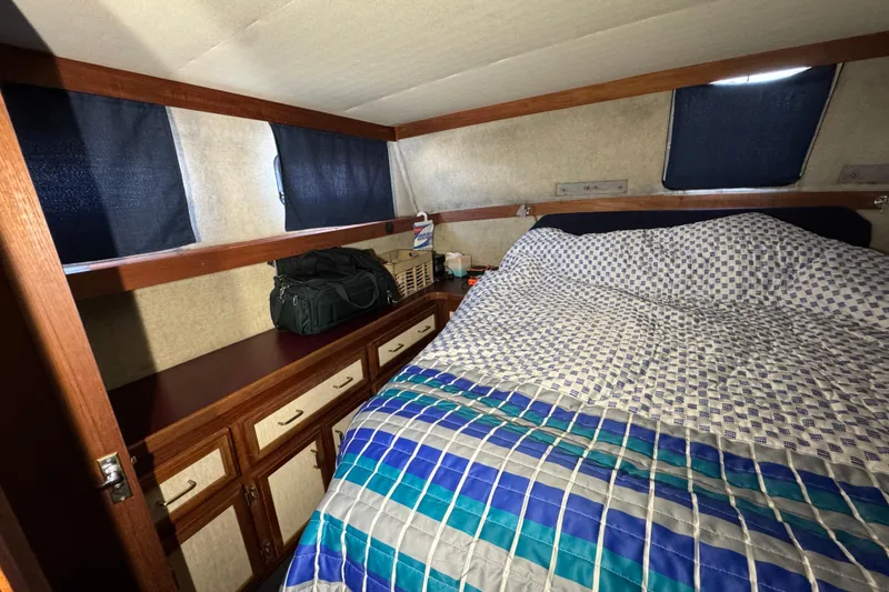1985 Carver 3607 Aft Cabin Motor Yacht bedroom with patterned bedding and storage cabinets.