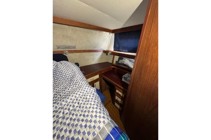 1985 Carver 3607 Aft Cabin Motor Yacht interior with cozy bed and wooden cabinetry.