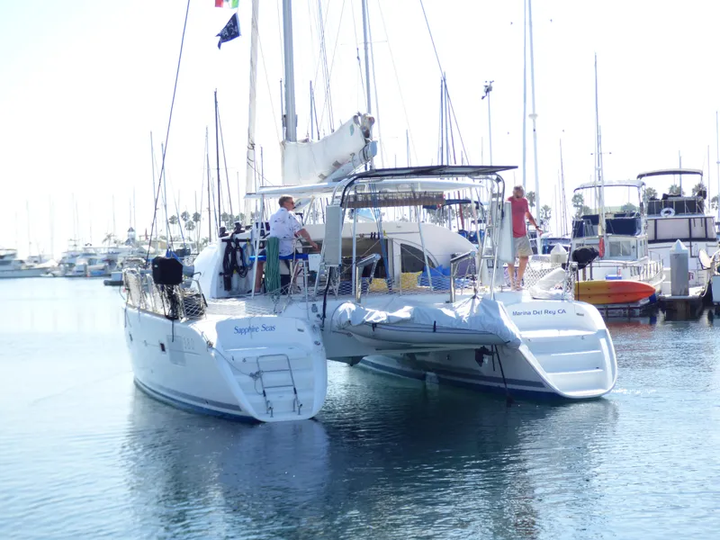 2015 Lagoon 380 catamaran docked in a marina with people on board.