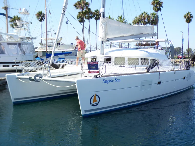 2015 Lagoon 380 catamaran docked in marina with palm trees in background.