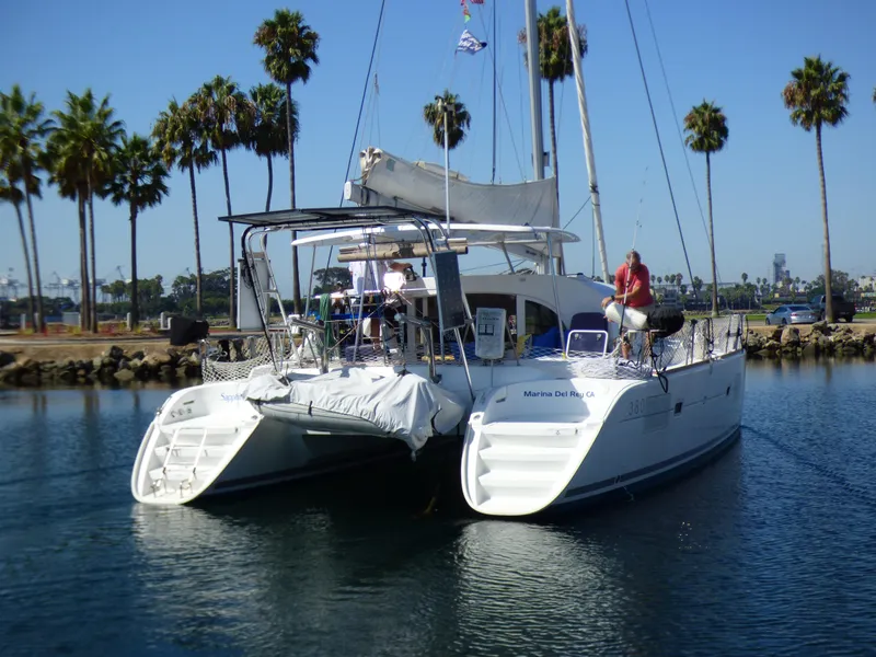 2015 Lagoon 380 catamaran docked in a sunny marina with palm trees.