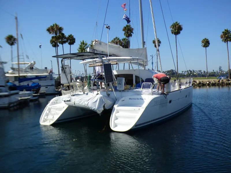 2015 Lagoon 380 catamaran docked in a marina with palm trees in the background.
