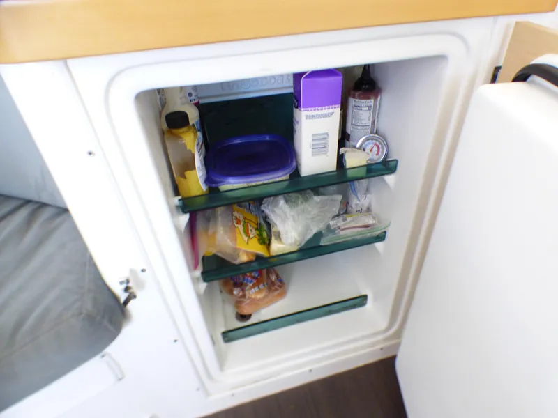 Small refrigerator inside a 2015 Lagoon 380 catamaran, stocked with various food items.