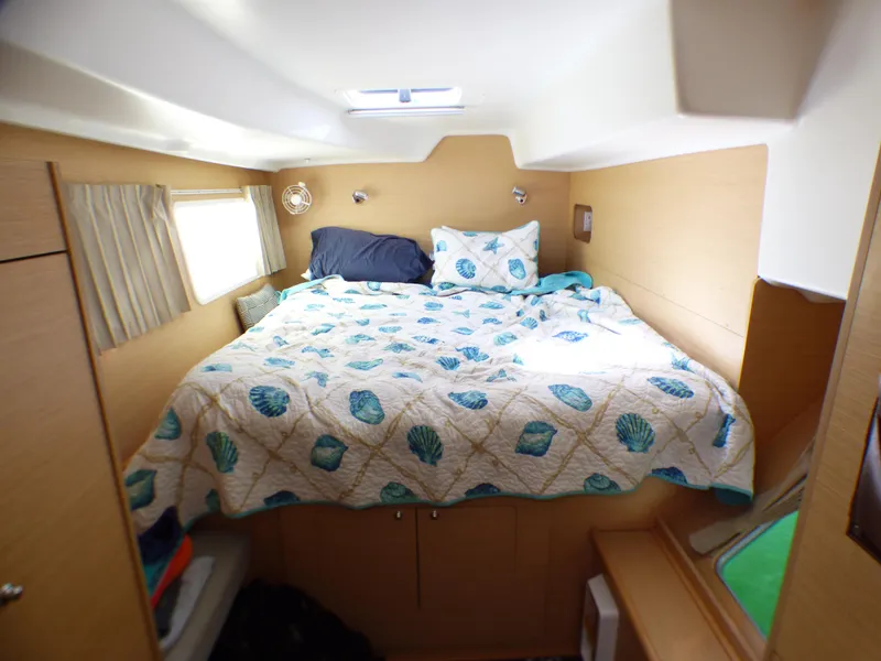 Cozy cabin interior of 2015 Lagoon 380 catamaran with nautical-themed bedding.