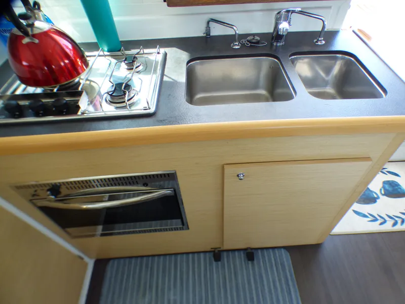 Compact kitchen in a 2015 Lagoon 380 catamaran with dual sinks and stove.