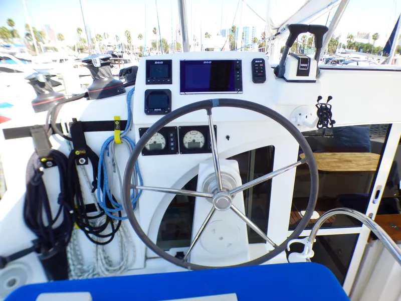 Steering wheel and controls of a 2015 Lagoon 380 catamaran in a marina setting.