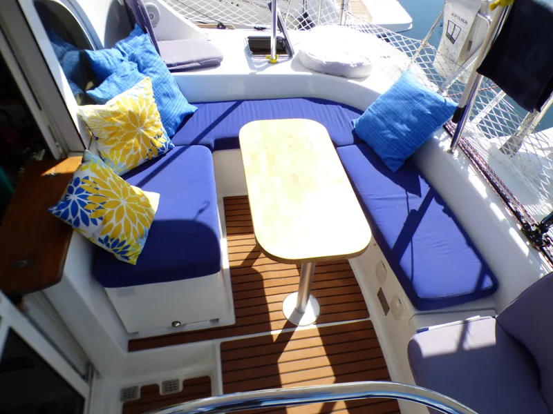 Cozy seating area on 2015 Lagoon 380 catamaran with blue cushions and wooden table.