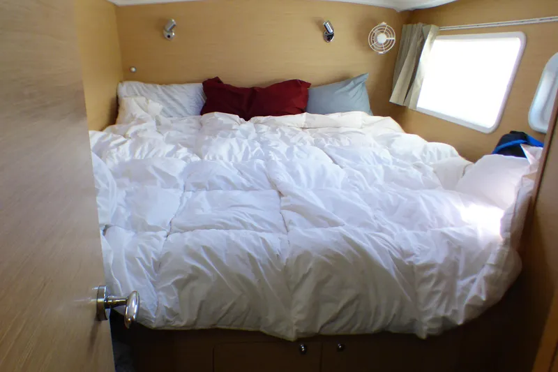 Cozy bedroom in 2015 Lagoon 380 catamaran with white bedding and natural light.